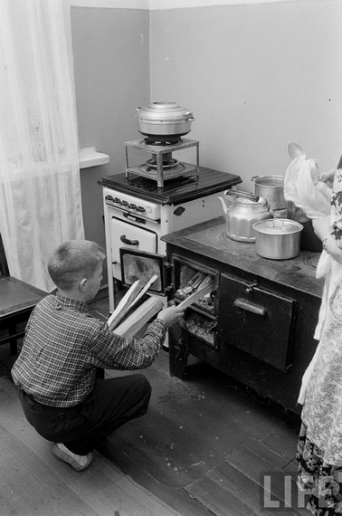 СССР, 1955 г. В семью ленинградского рабочего привезли газовую плиту, но еще не подключили. Пока готовят на старой, которую топят дровами. Фотограф Эд Кларк, журнал LIFE. 